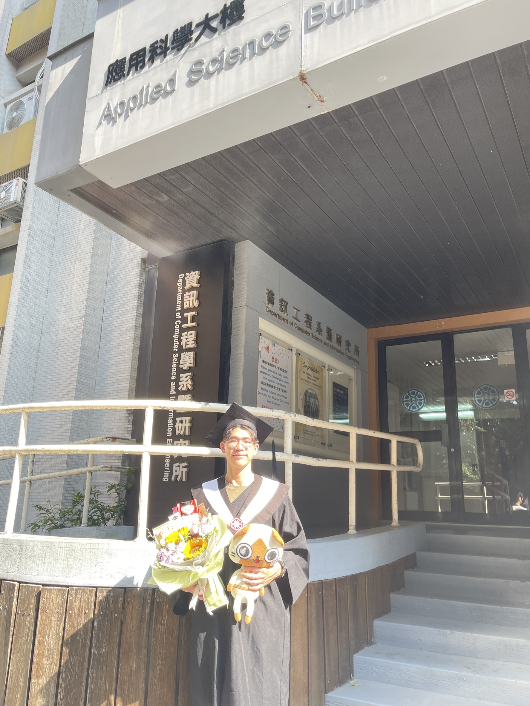 李曜宇穿著畢業服站在師大資工系館前